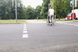 Man crossing the street while pushing a man in a wheel chair